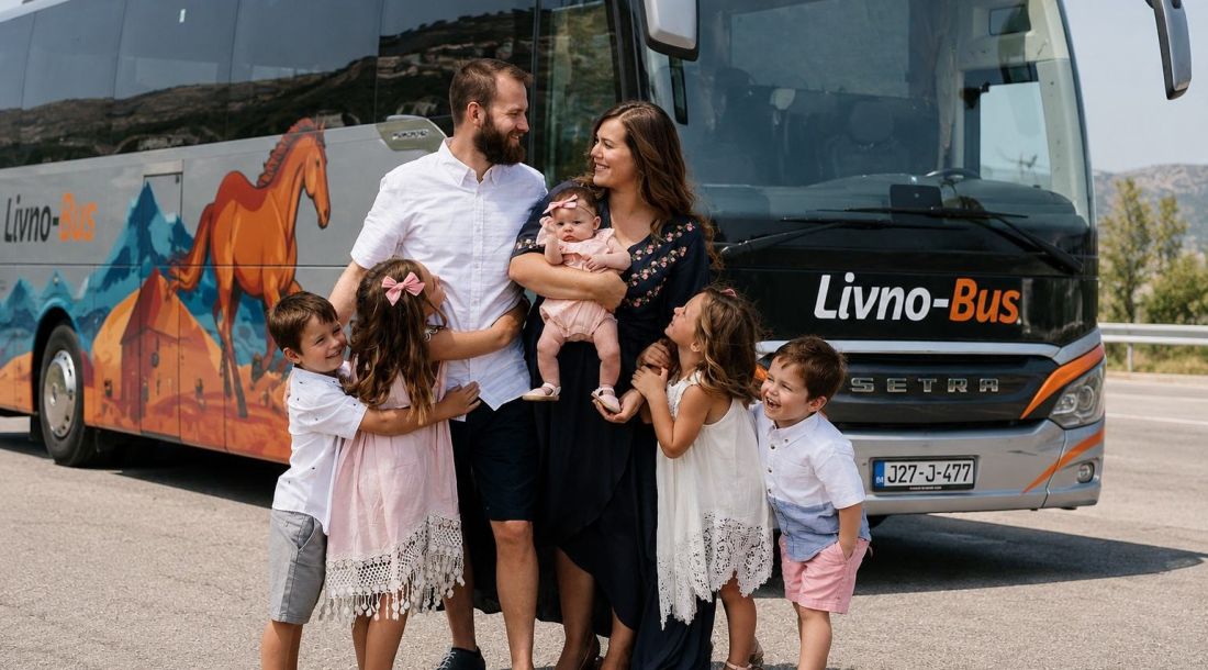 Obitelj s djecom stoji ispred autobusa Livno Bus prije polaska na put.