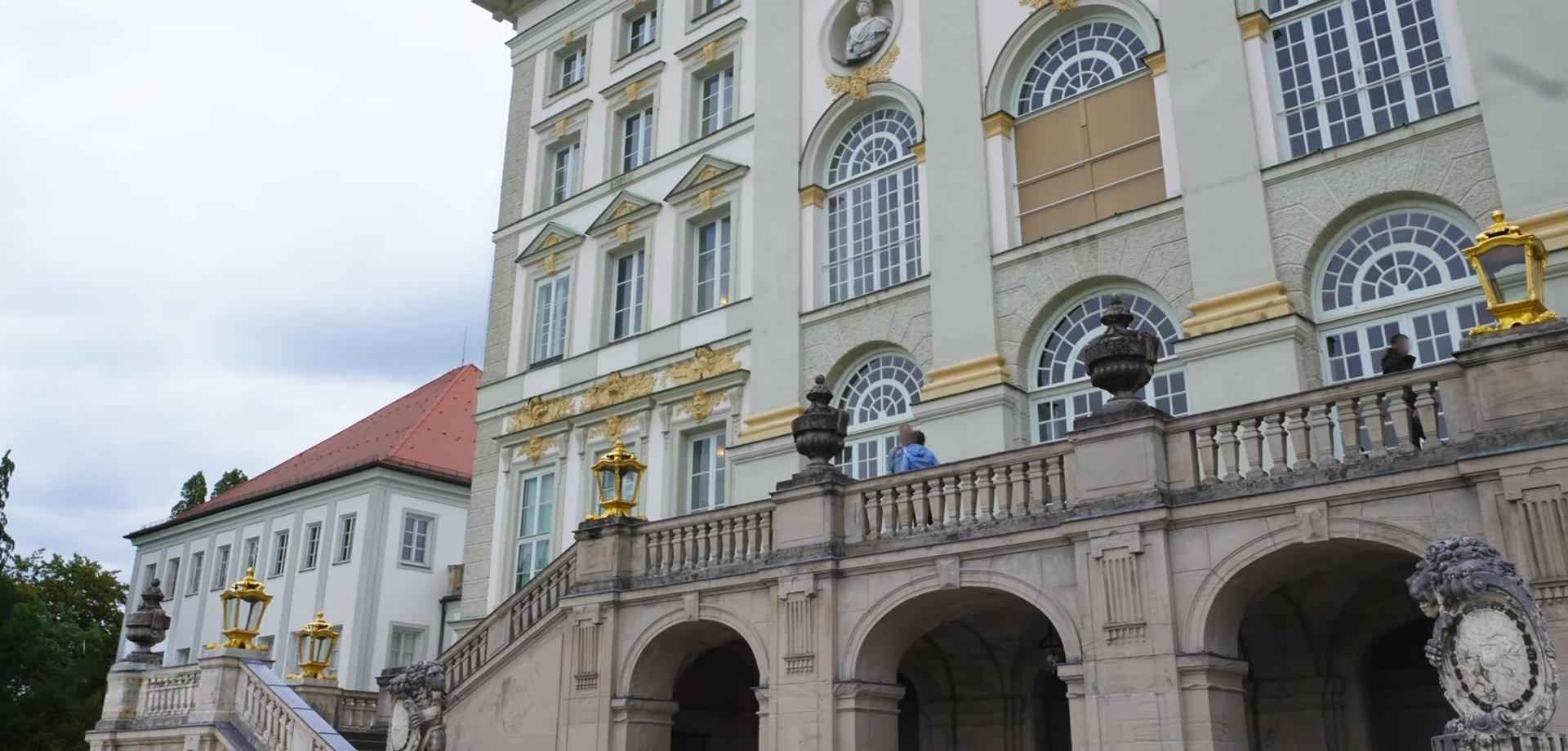 Vanjski pogled na dvorac Nymphenburg u Münchenu s velikim bijelim pročeljem i arhitektonskim detaljima.