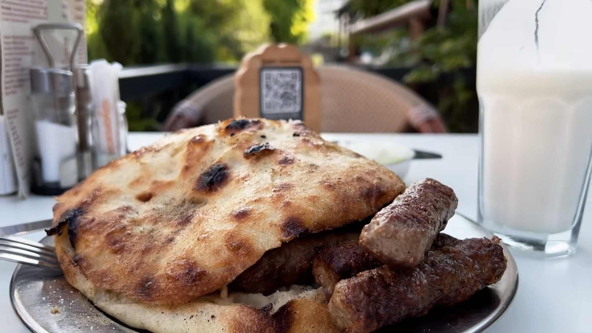Porcija travničkih ćevapa u pečenom somunu na tanjuru u restoranu.