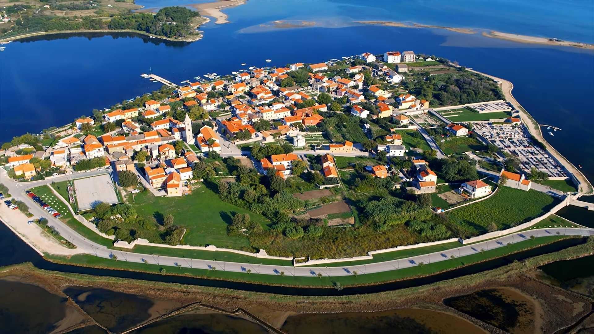 Pogled iz zraka na povijesnu jezgru Nina, kamene mostove i more koje okružuje grad.