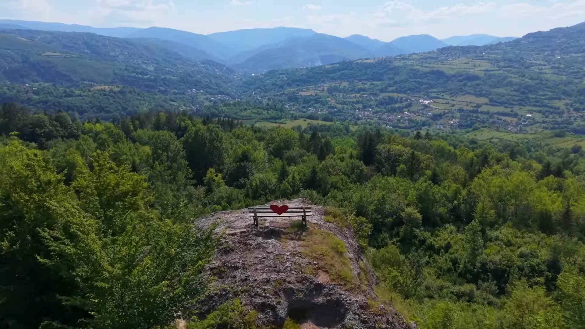 Klupa na stjenovitom vidikovcu s pogledom na šume i planine u okolici Jajca.