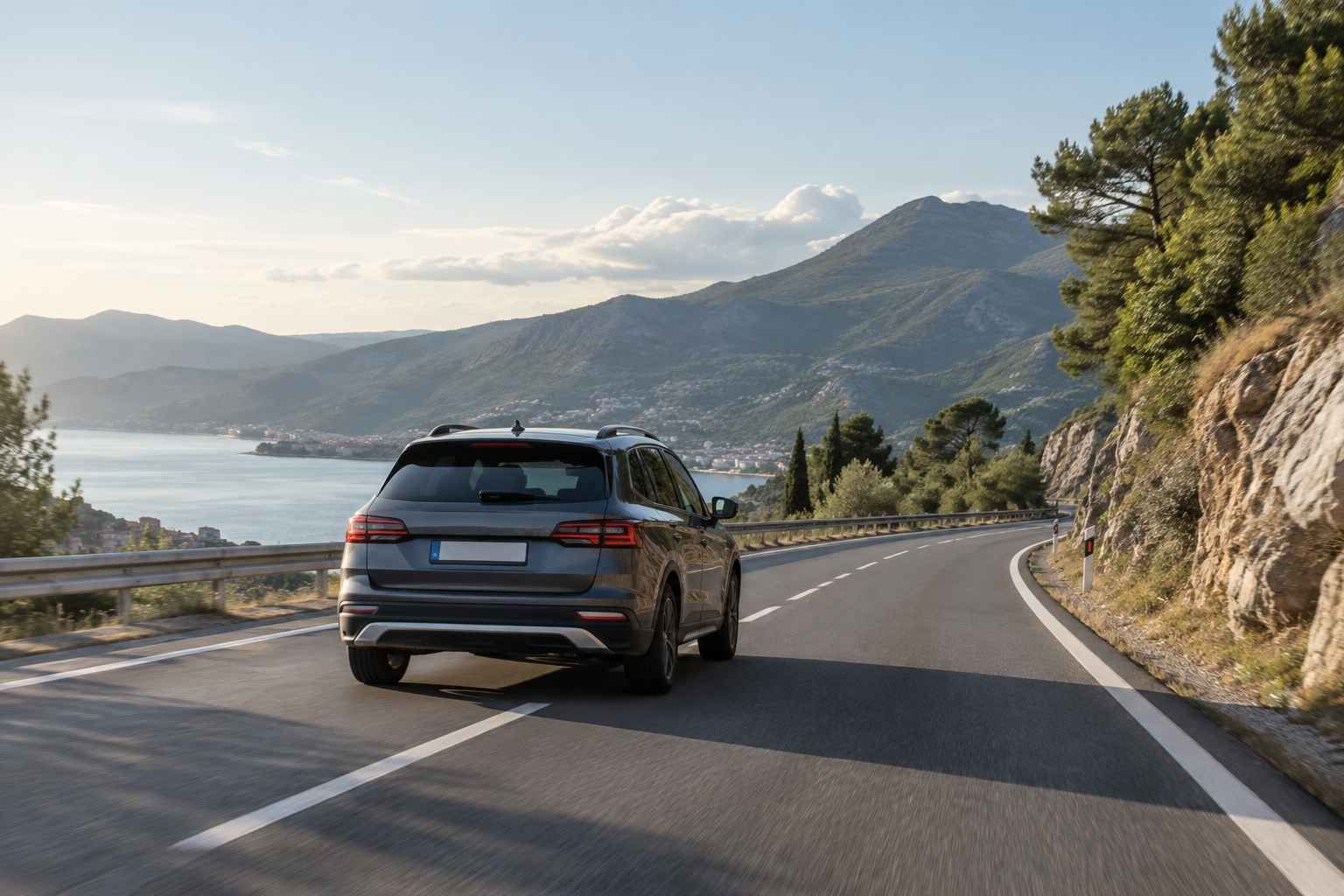 Sivi SUV na planinskoj cesti uz more tijekom putovanja automobilom.