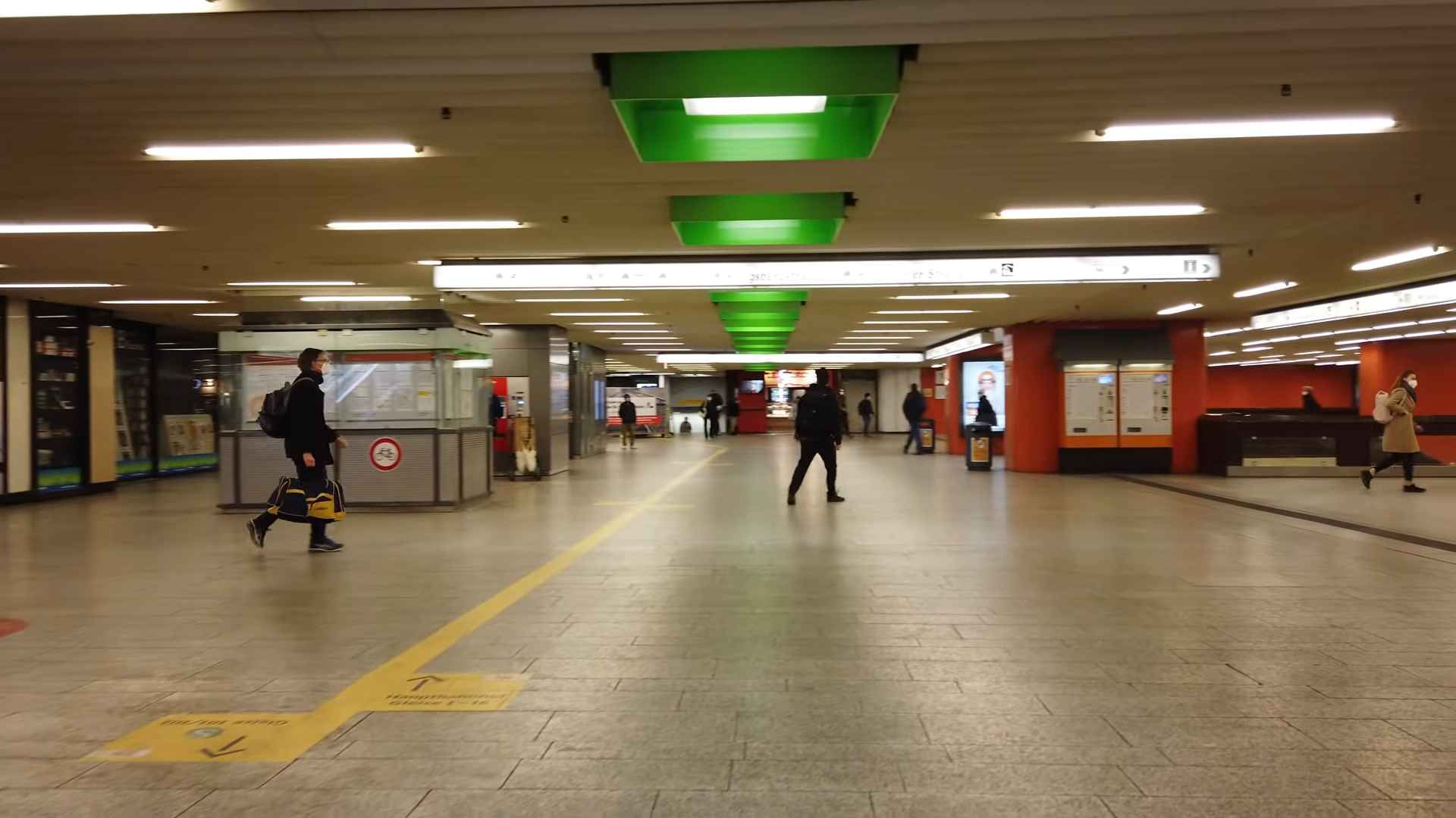 Unutrašnjost podzemne stanice S-Bahn u Stuttgartu s putnicima, oznakama smjera i prolazima prema peronima.