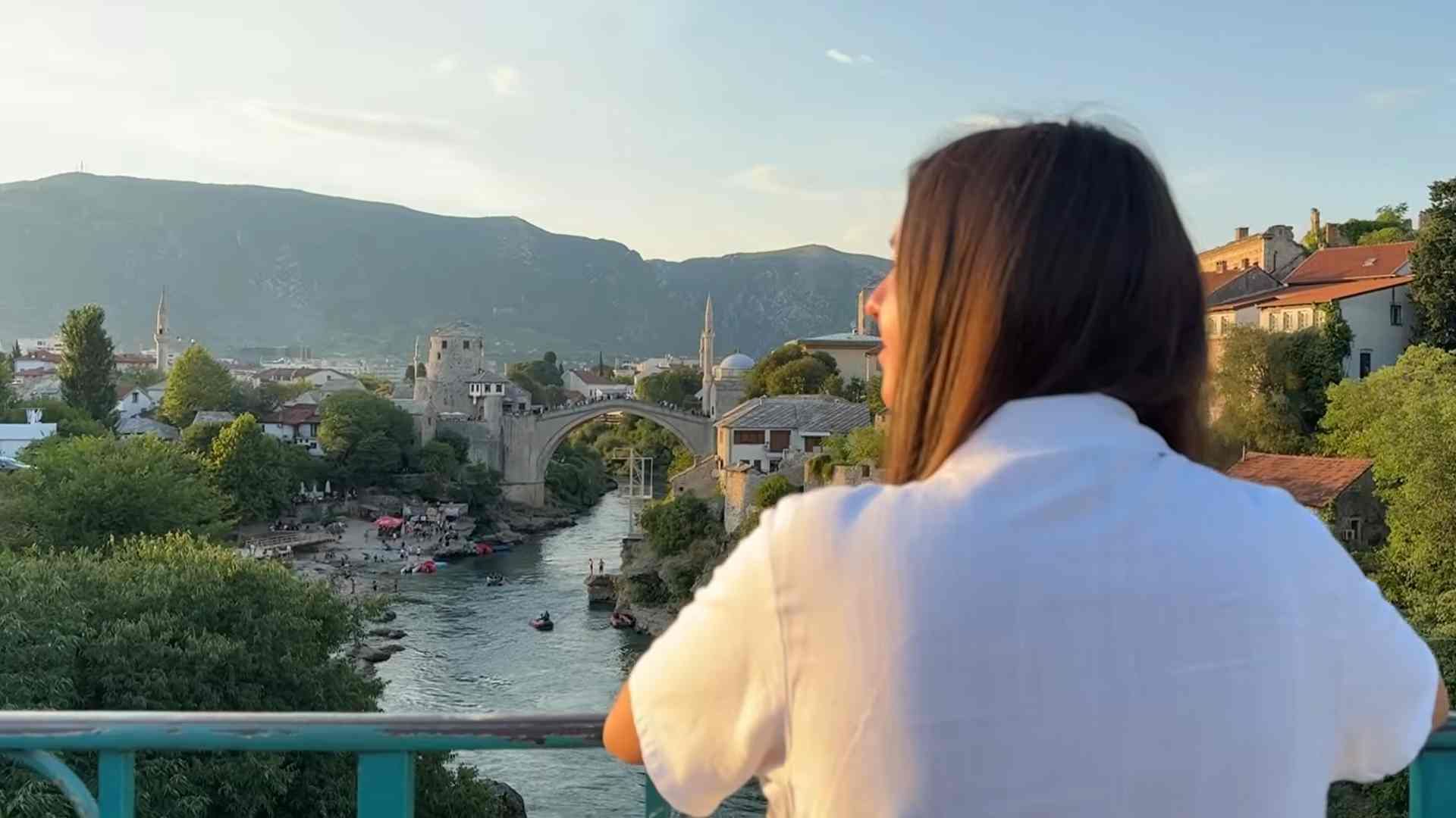 Osoba promatra Stari most i rijeku Neretvu s vidikovca u Mostaru.