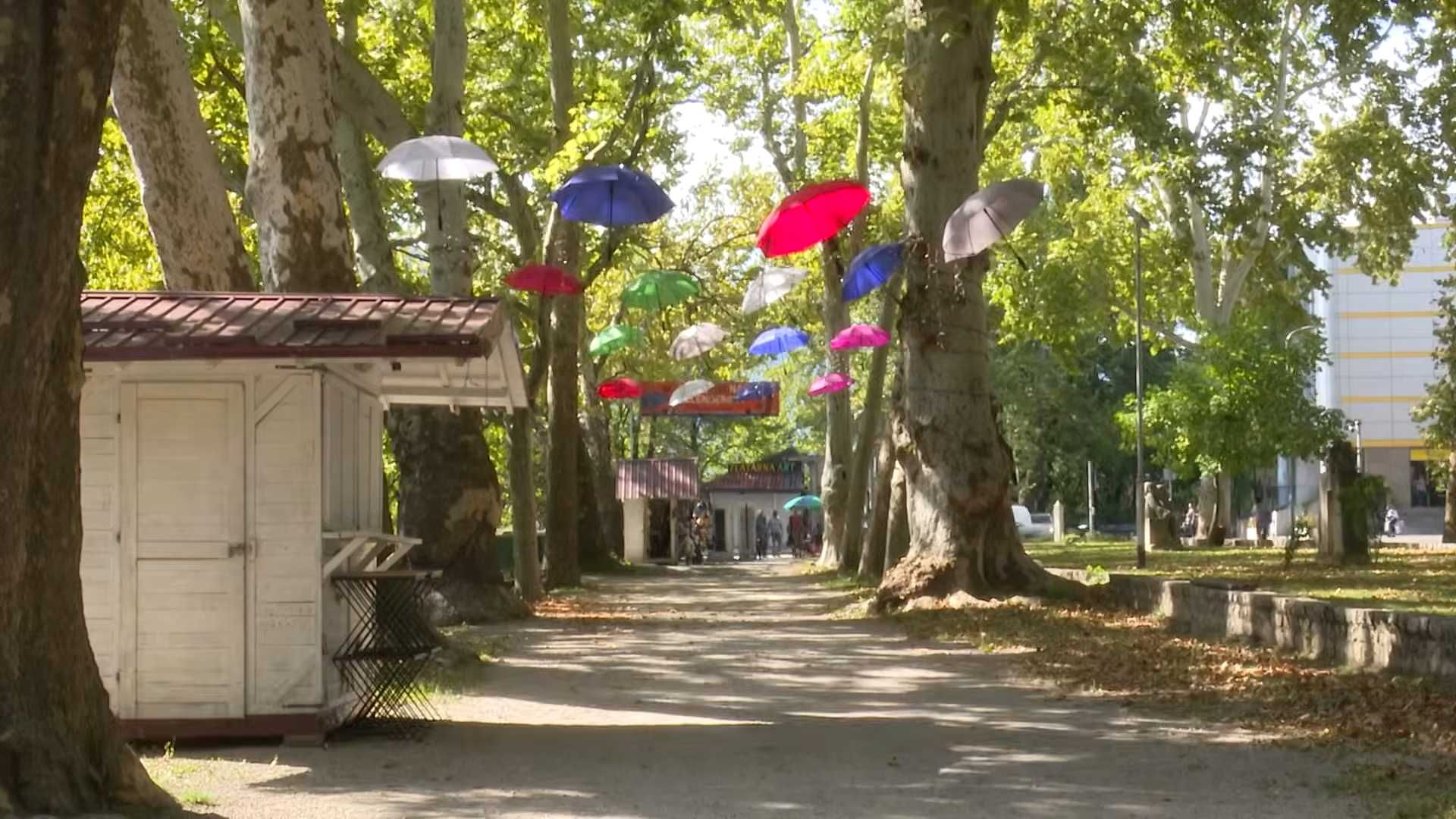 Šetnica kroz park Gelenderi u Bihaću s ukrasnim kišobranima iznad staze.