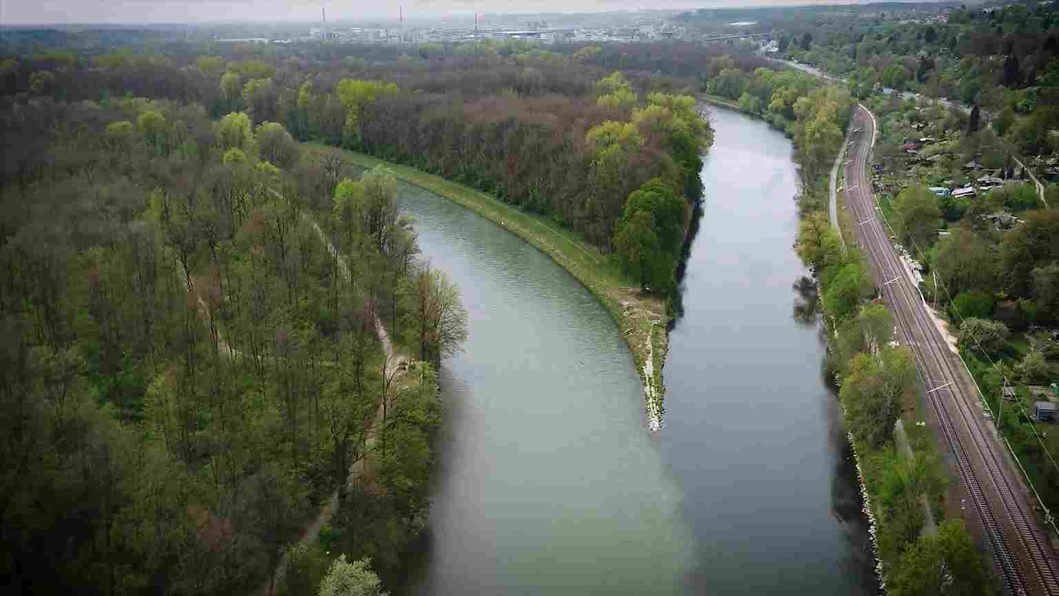 Panoramski pogled na Dunav, zelene obale i željezničku prugu u okolici Ulma.