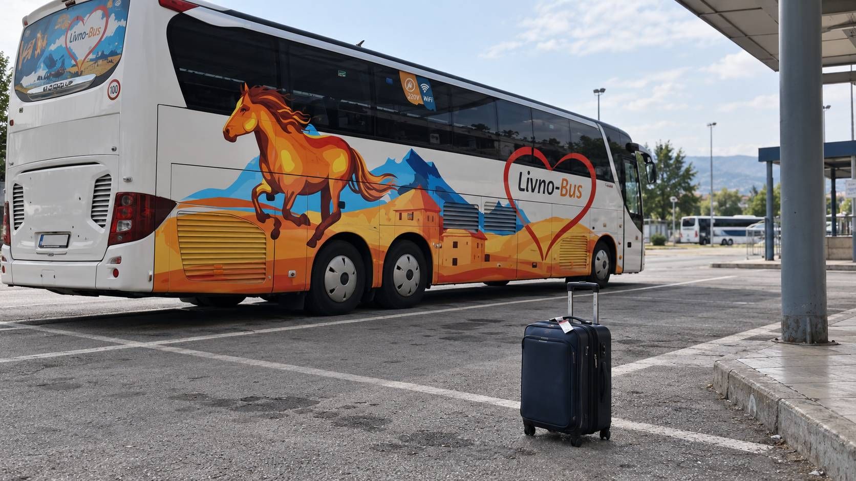 Tamnoplavi putni kofer na parkiralištu ispred autobusa Livno-Busa.