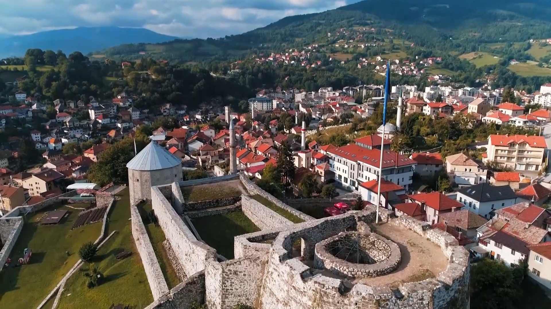 Pogled iz zraka na tvrđavu Stari grad Travnik, kamene zidine i okolne gradske kuće.
