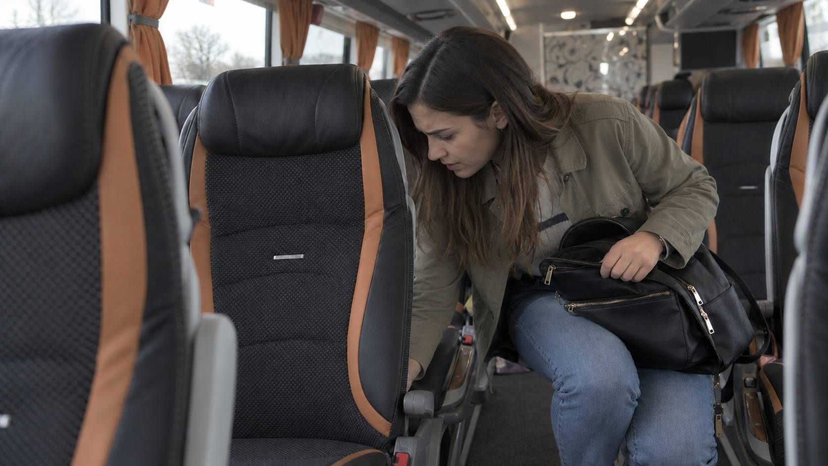 Žena s crnom torbom pregledava prostor između sjedala u autobusu Livno-Busa.